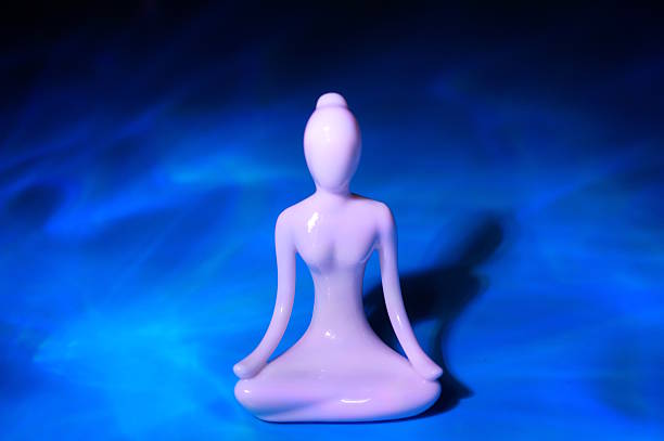 Porcelain figurine on a blue background. A meditative pose.