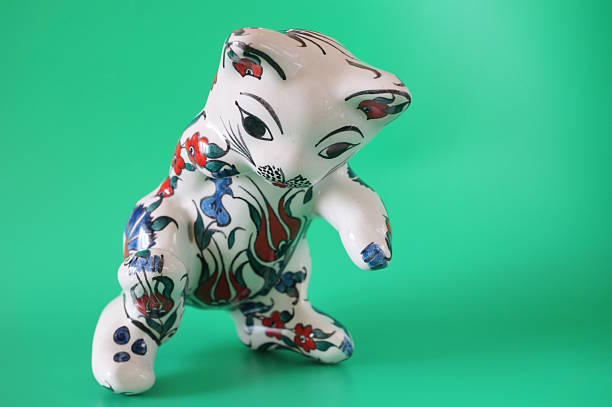 Ceramic painted cat figurine on a green background.