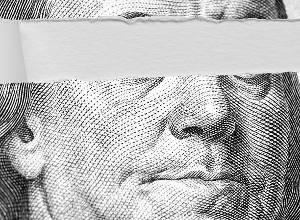 This image features a U.S. one-hundred-dollar bill with a white strip covering the eyes of Benjamin Franklin’s portrait, representing anonymity or censorship. Suitable for financial anonymity discussions, economic critiques, or symbolic representations of money and identity.