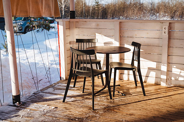 istock A beautifully crafted wooden table, accompanied by its matching chairs, is elegantly arranged on a serene patio blanketed in fresh, white snow, forming a peaceful and inviting winter scene 2210761392