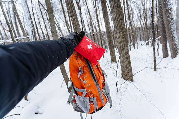istock A person holds a bright red first aid kit above an orange backpack in soft snow, set against a stunning winter landscape filled with icy flakes and invigorating cold air 2210761443