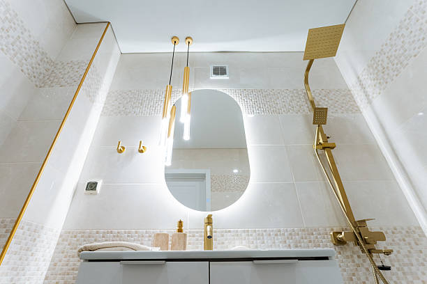A bathroom with a white toilet, sink, and mirror. The bathroom has a clean and modern design, with a glass shower door and a wooden vanity