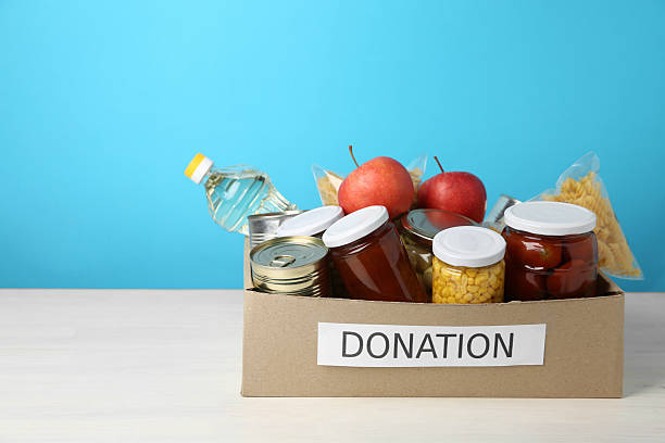 istock Different food products for donation in box on table against light blue background, space for text 2210778459