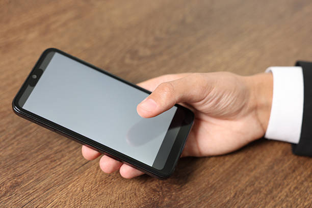 istock Man unlocking smartphone with fingerprint scanner at wooden table, closeup 2210778584