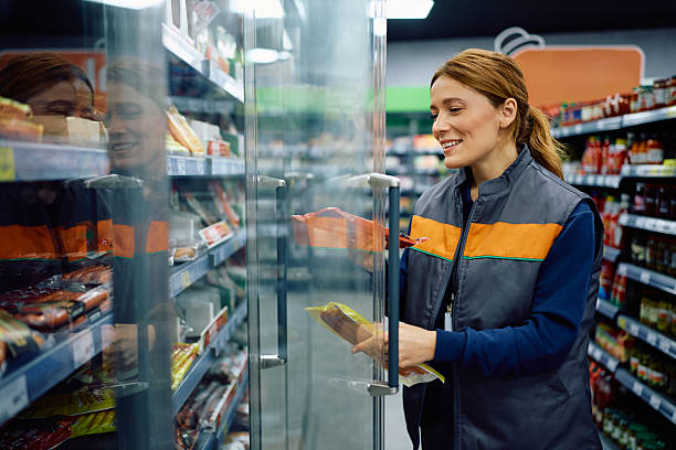 istock Happy supermarket worker stacking products in a refrigerator at the store. 2210783908