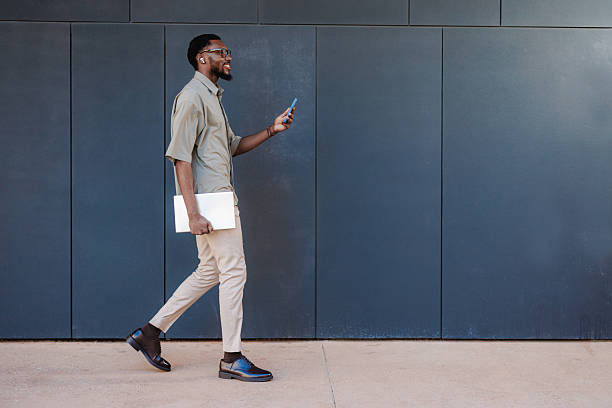 istock Professional man walking while checking phone and holding a laptop 2210787210