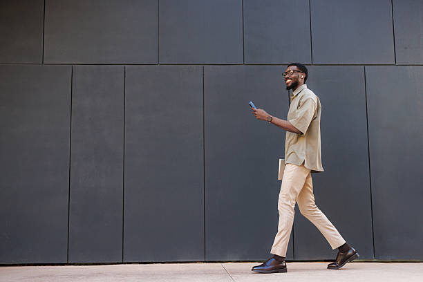 istock Confident young man walking outdoors while holding a smartphone 2210787213