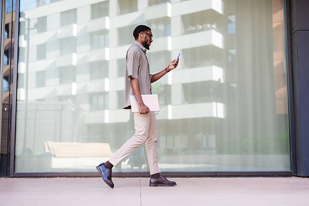 istock Young professional walking and using smartphone outdoors by a modern building 2210787219