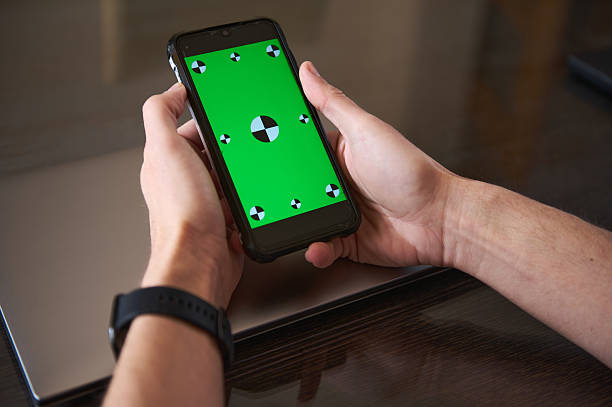 istock Person Holding Smartphone With Green Screen Over Laptop 2210788837