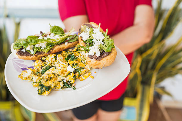 istock Woman holding plate with molletes and scrambled eggs with spinach 2210789621