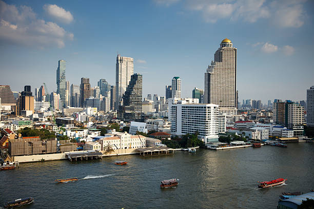 Wide shot of Khlong San and Sathon in Bangkok, Thailand, looking east across the Chao Phraya River from a high window in Thon Buri. Shot during the day. This file is part of a series of shots taken at different times from the same location, matching shots are available.