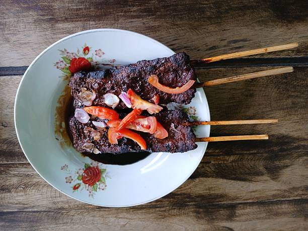 Satay sapi (beef skewered). Served with soy sauce, chili and tomato. The satay is originated in Indonesia