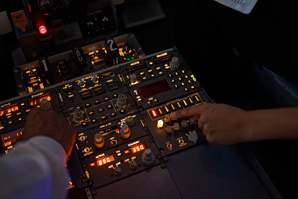 A photograph looking down above two pairs of African-American hands moving over flight instrumentation.