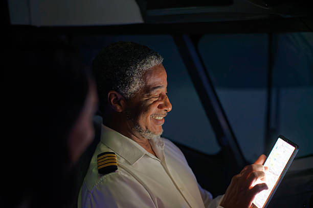 A commercial plane pilot smiles while he manipulates a digital tablet.