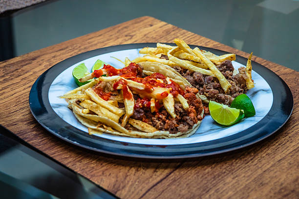 Mexican beef jerky tacos with red sauce and fries on top, and lemons on the side, tacos from Mexico City and Mexico State