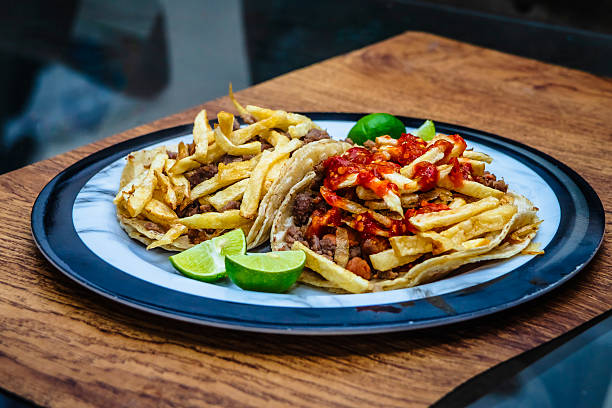 Mexican beef jerky tacos with red sauce and fries on top, and lemons on the side, tacos from Mexico City and Mexico State