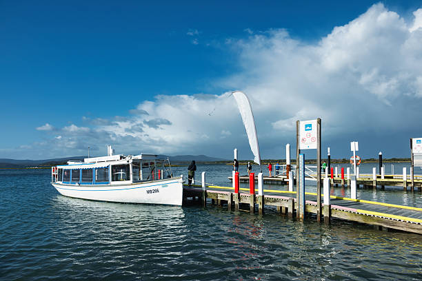 People fish at the Mallacoota Wharf in Mallacoota, Victoria, Australia on a sunny day.