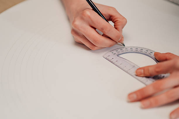 istock Architect drawing circles with pencil and protractor on white paper 2210800256