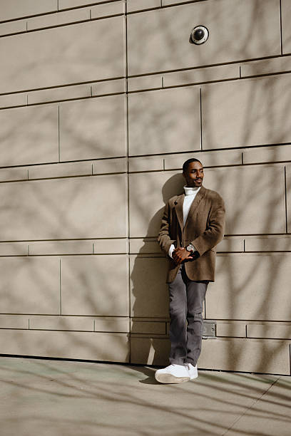 istock Stylish Man Leaning Against Wall on Sunny Day With Shadows 2210800712