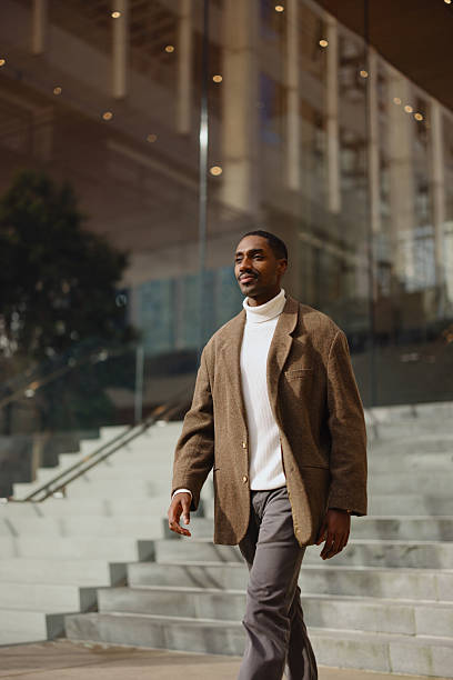 istock Confident Man Walking Outside Modern Office Building on Sunny Day 2210800728