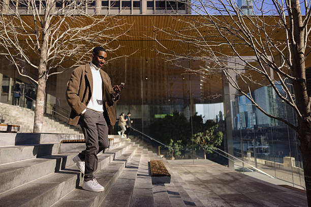 istock City Professional Uses Smartphone While Strolling Downstairs on a Bright Day 2210800739