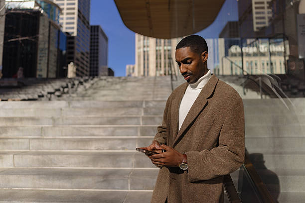 istock Stylishly Dressed Man Checking Phone Against Urban Stairs Background 2210800759