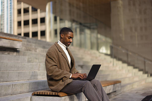 istock Man Working on Laptop While Sitting Outdoors on Concrete Stairs 2210800763