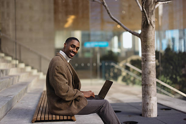 istock Business Professional Smiling Outdoors While Using Laptop on Wooden Bench 2210800787