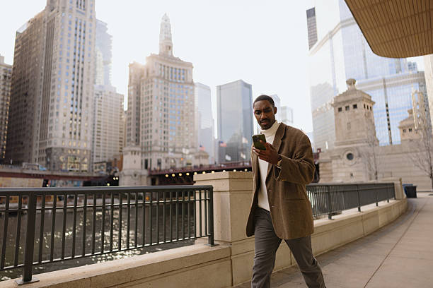istock Urban Professional Using Smartphone While Walking Near Riverfront and City Buildings 2210800832