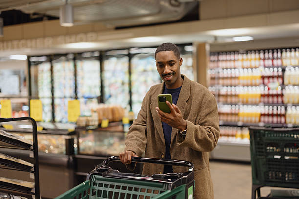 istock Man Using Smartphone While Shopping in Grocery Store with Cart 2210800894