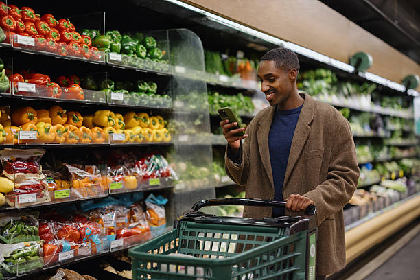 istock Man Shopping for Vegetables While Using Smartphone in Grocery Store 2210800911
