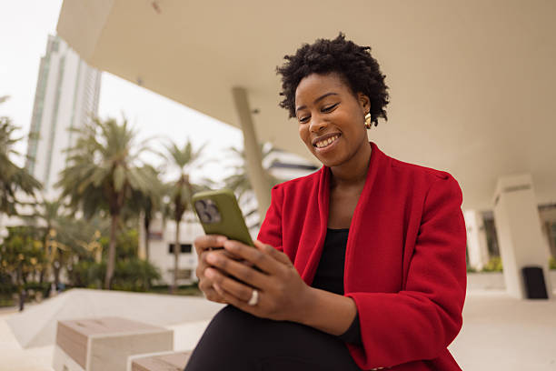 istock Smiling Woman Using Smartphone Outdoors in Urban Setting With Palm Trees 2210800934