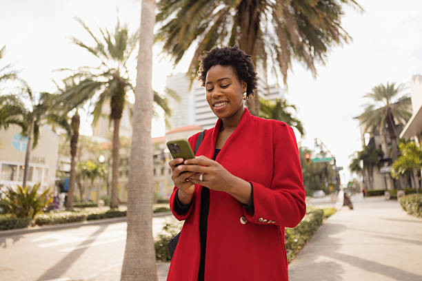 istock Woman Smiling While Browsing Smartphone Outdoors on a Sunny Day 2210800951