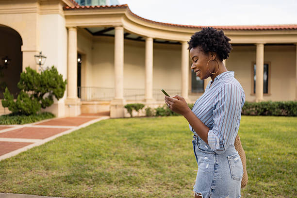 istock Smiling Woman Using Smartphone Outdoors Near Elegant Building with Arched Design 2210800963