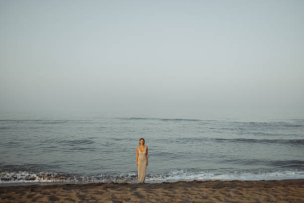 Woman Standing Alone on a Peaceful Ocean Shoreline at Dawn