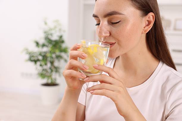 istock Woman drinking water with lemon indoors, closeup. Space for text 2210802031