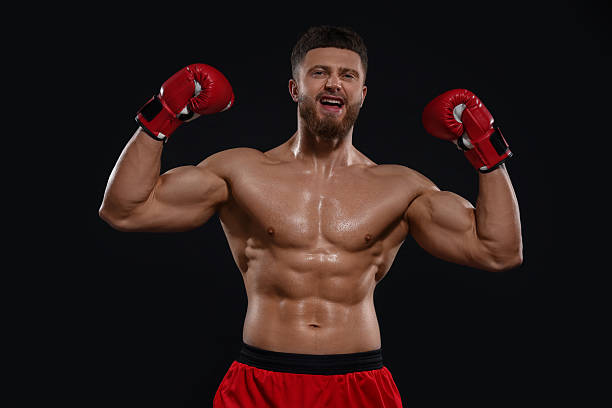 istock Man in boxing gloves celebrating victory on black background 2210803424