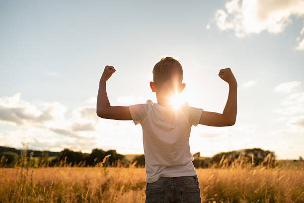 istock Strong little boy flexing muscles at the meadow during sunset. 2210803601