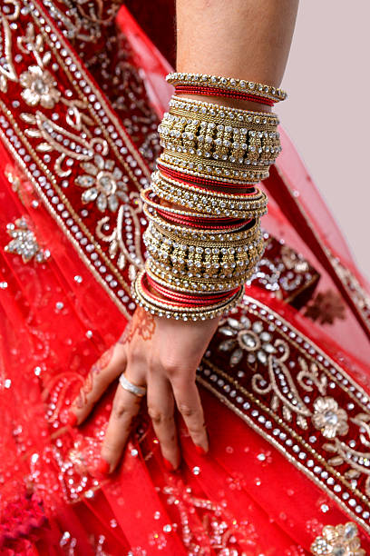 istock Indian Bride’s Arm Adorned with Red and Gold Bangles 2210804823