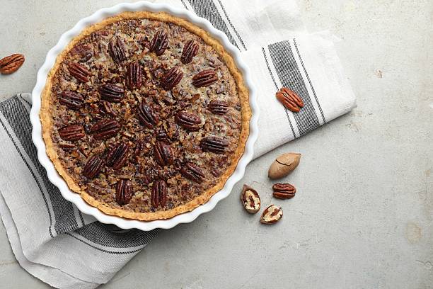 istock Delicious pecan pie in baking dish and fresh nuts on gray textured table, top view 2210805045