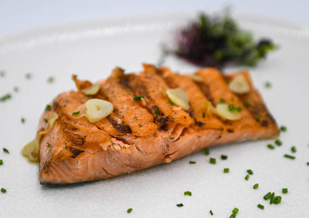 istock Salmon fillet with garlic and herbs on a white plate. 2210806835