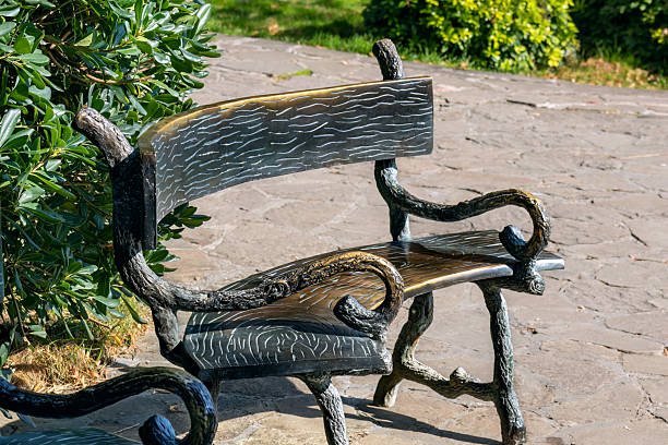 istock Forged metal bench imitating tree branches in green park landscape. Stylish element. 2210807030