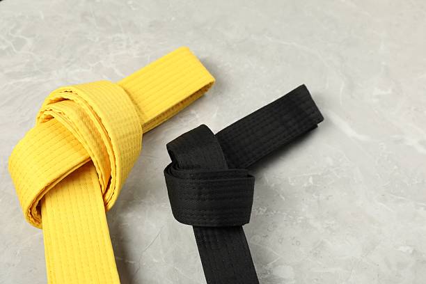 istock Black and yellow karate belts on gray marble background 2210807158