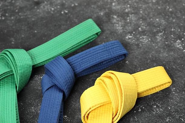 Colorful karate belts on gray background, closeup