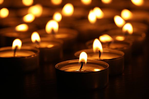 istock Burning candles on table in darkness, closeup 2210808063