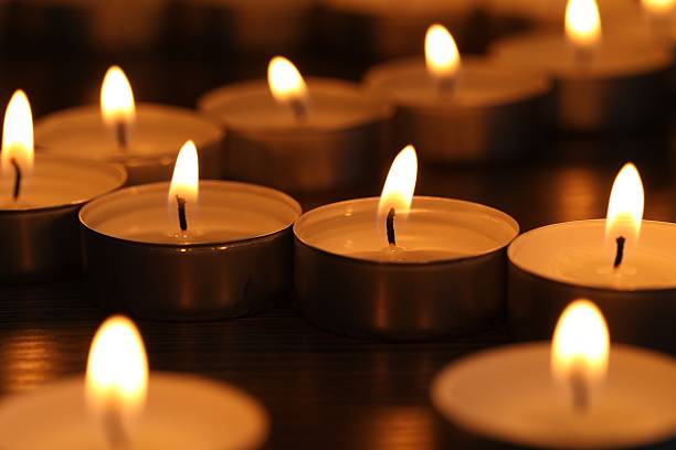 istock Burning tealight candles on dark surface, closeup 2210808074