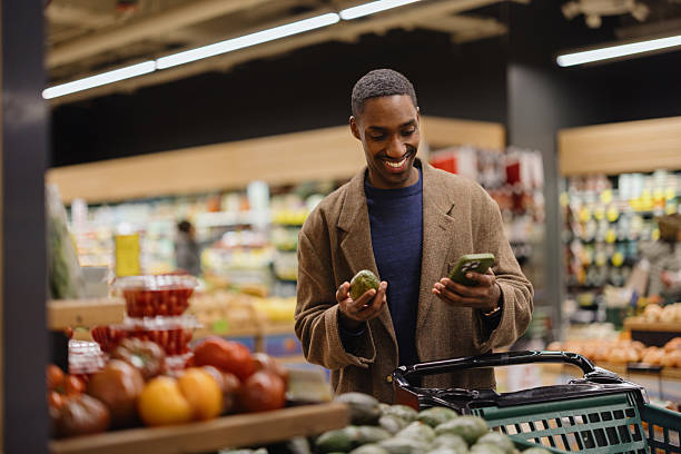 istock Man Smiling While Grocery Shopping and Using Phone in Produce Section 2210809135