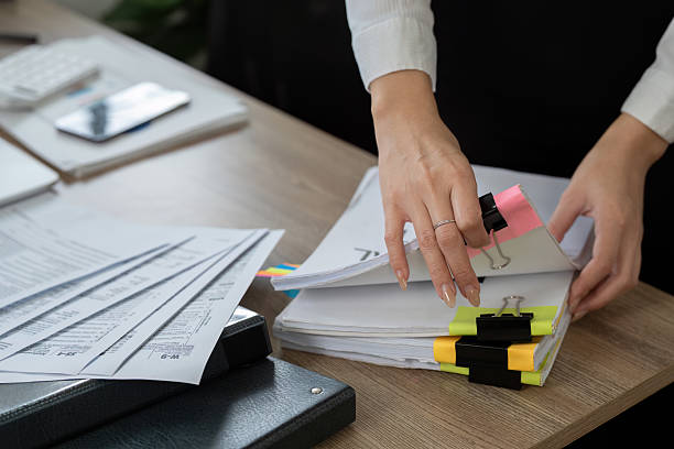 istock Professional accountant organizing financial documents on a desk with colorful clips and reports. 2210813307