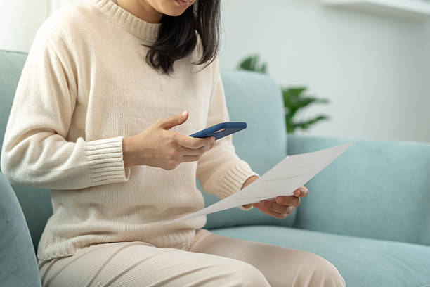 istock woman use phone scan barcode or QR codes to pay credit card bill after receiving document invoice. payment, receive, paying electricity, digital payments, technology, scanning, financial transactions 2210813378
