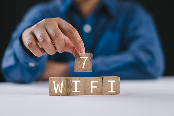 istock WiFi 7 CERTIFIED. Hand hold wooden cube blocks with WiFi-7 symbol. Transformation technology and upgrade router for high internet speed to support IoT and smartphones. Enhances network performance. 2210813402